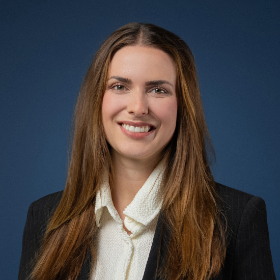 Porträt von Ann-Kristin Wagner in dunklem Blazer vor dunkelblauem Hintergrund.