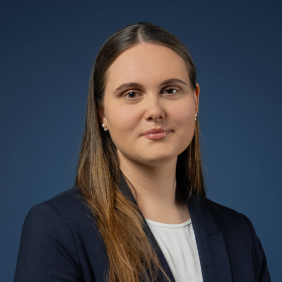 Porträt von Fiona Maria Dick in dunklem Blazer vor dunkelblauem Hintergrund.