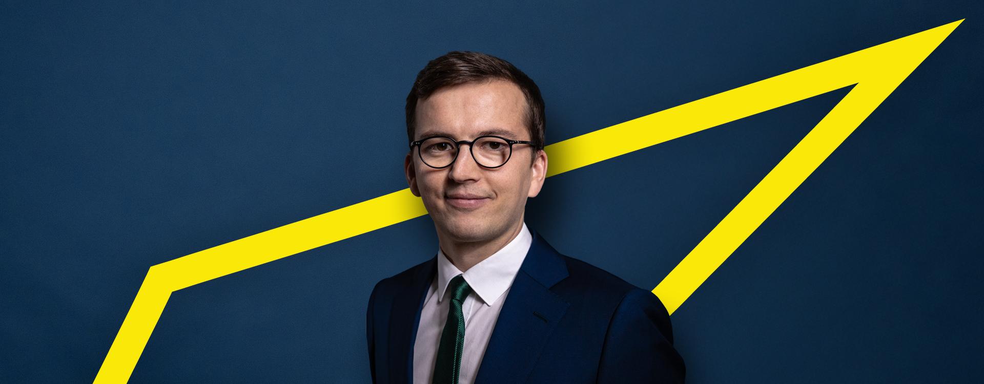 Porträt von Nils Schlenkhoff vor dunkelblauem Hintergrund mit gelbem Pfeilmotiv.